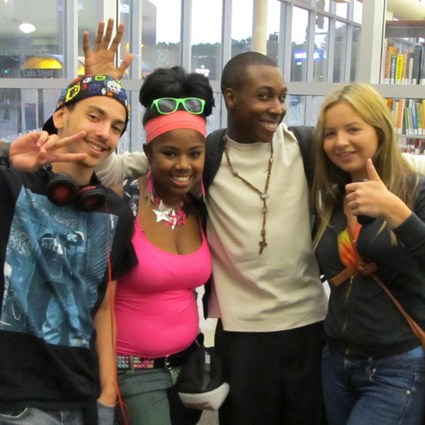 Four teens pose for the camera in a Minneapolis library. Two of them are actors playing students questioning the value of high school education, in the authentic fiction Ed Zed Omega.